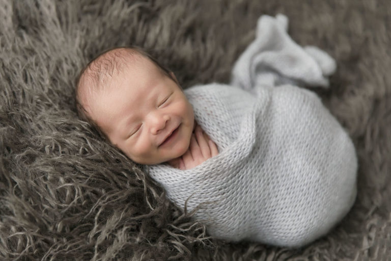 Newborn smile in grey wrap